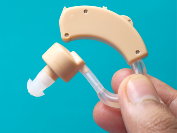 Behind-the-Ear hearing aid held up by fingers.