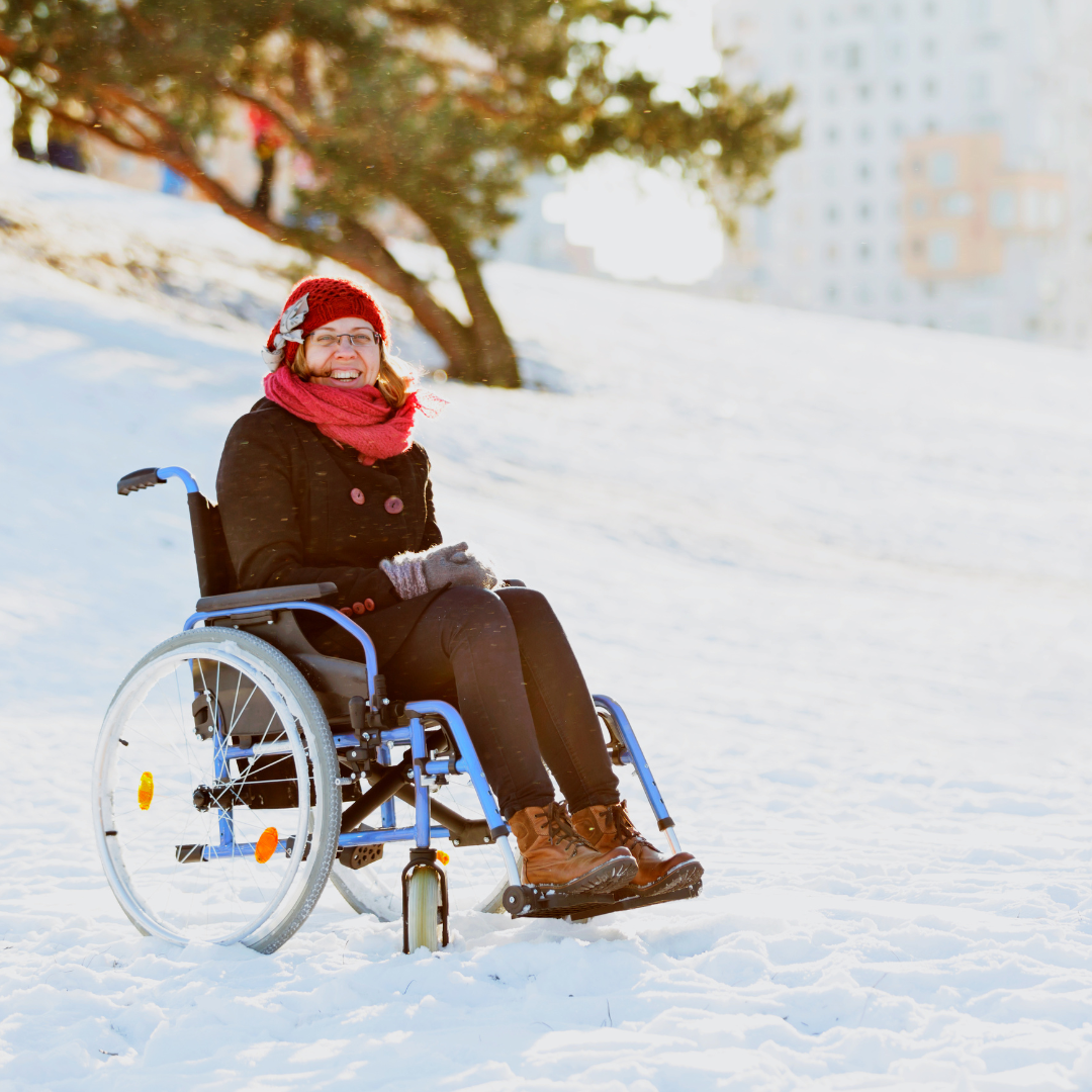Woman in wheelchair smiling in a snowy field.
