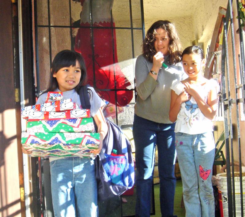 Tell Santa thank you! This little girl received gifts from USPS Operation Santa volunteers one Christmas Eve with her sisters looking on. Smiles all around!
