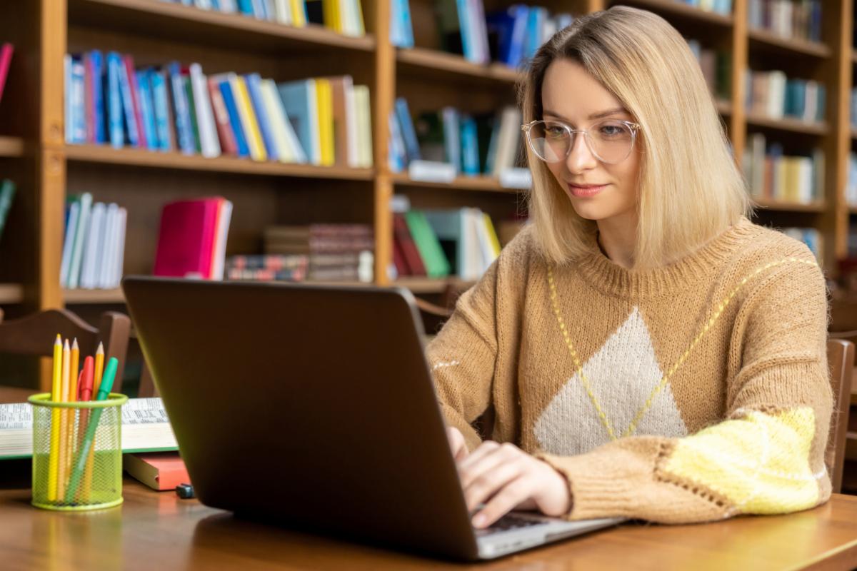 In the library. Young blonde woman working on a laptop in the library