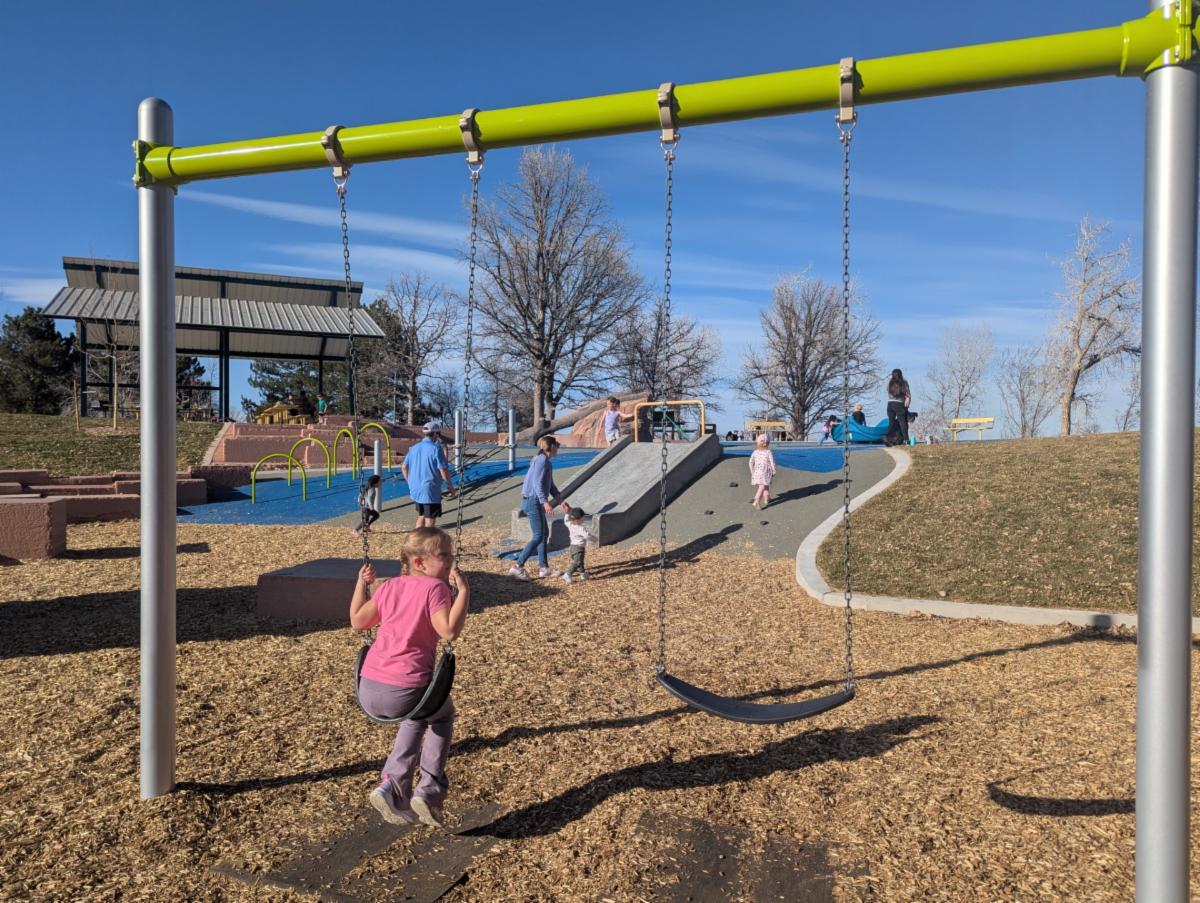 A child is on a new swing set at Loretto Heights Park. 
