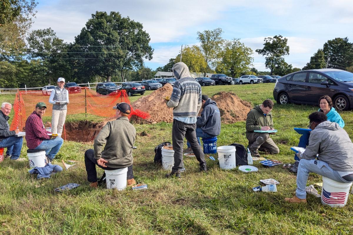 Group of professionals during a Soil Evaluator Training, sitting outside in a field.