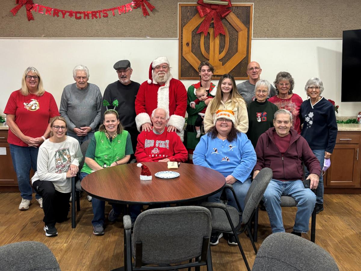 14 people stand or sit near Santa. 