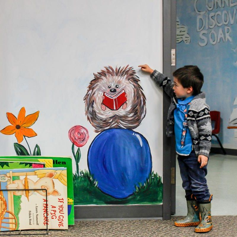 Little boy beside wall painted with a hedge hog