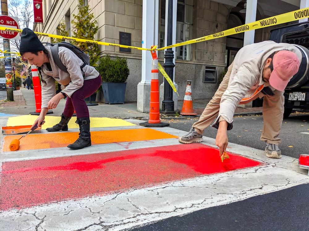 Image of two community members helping out with the crosswalk pride painting.