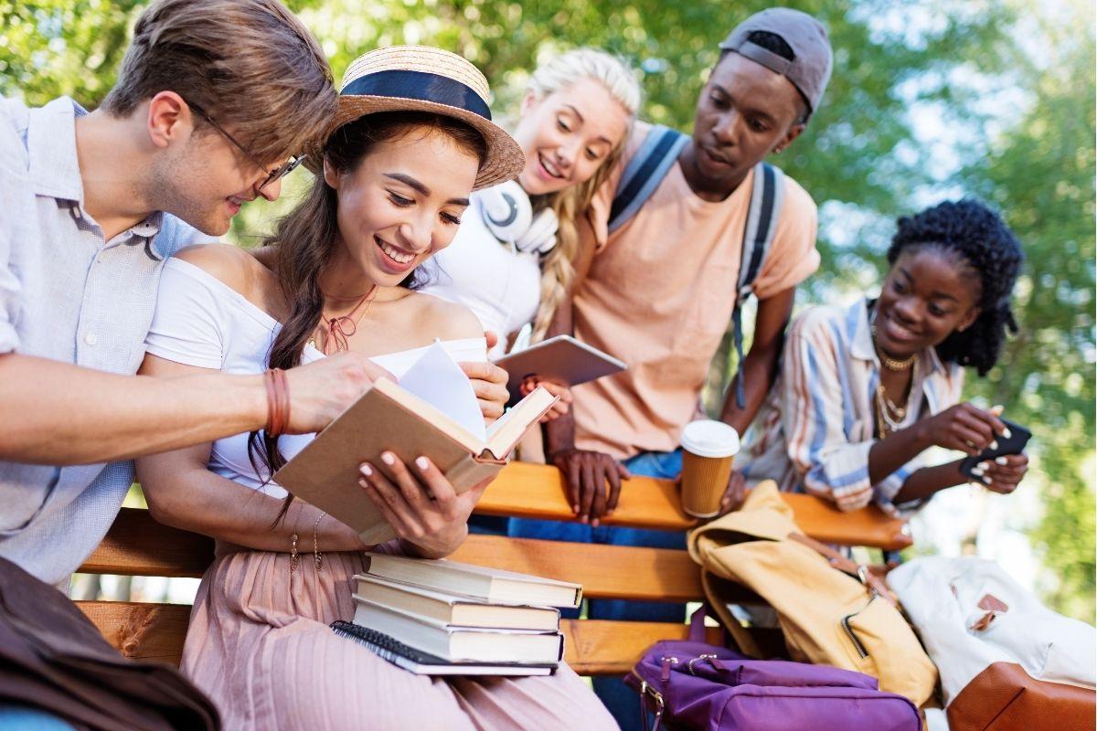 Students discussing something they are reading in their stacks of books.