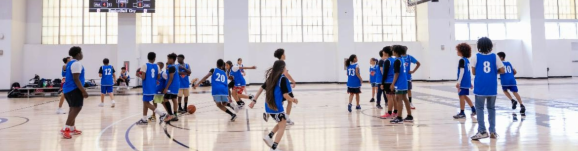 Students in a gym wearing blue jerseys playing basketball