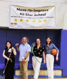Four adults smiling and holding fitness equipment standing under a Move-to-Improve All Star School banner