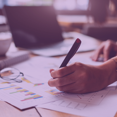 Close up photo of desk covered with small piles of application papers, hand writing on one paper, and laptop.