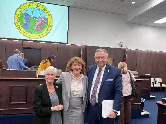 NC Senators Gale Adcock and Jim Burgin standing next to Erin Fraher in a meeting room.