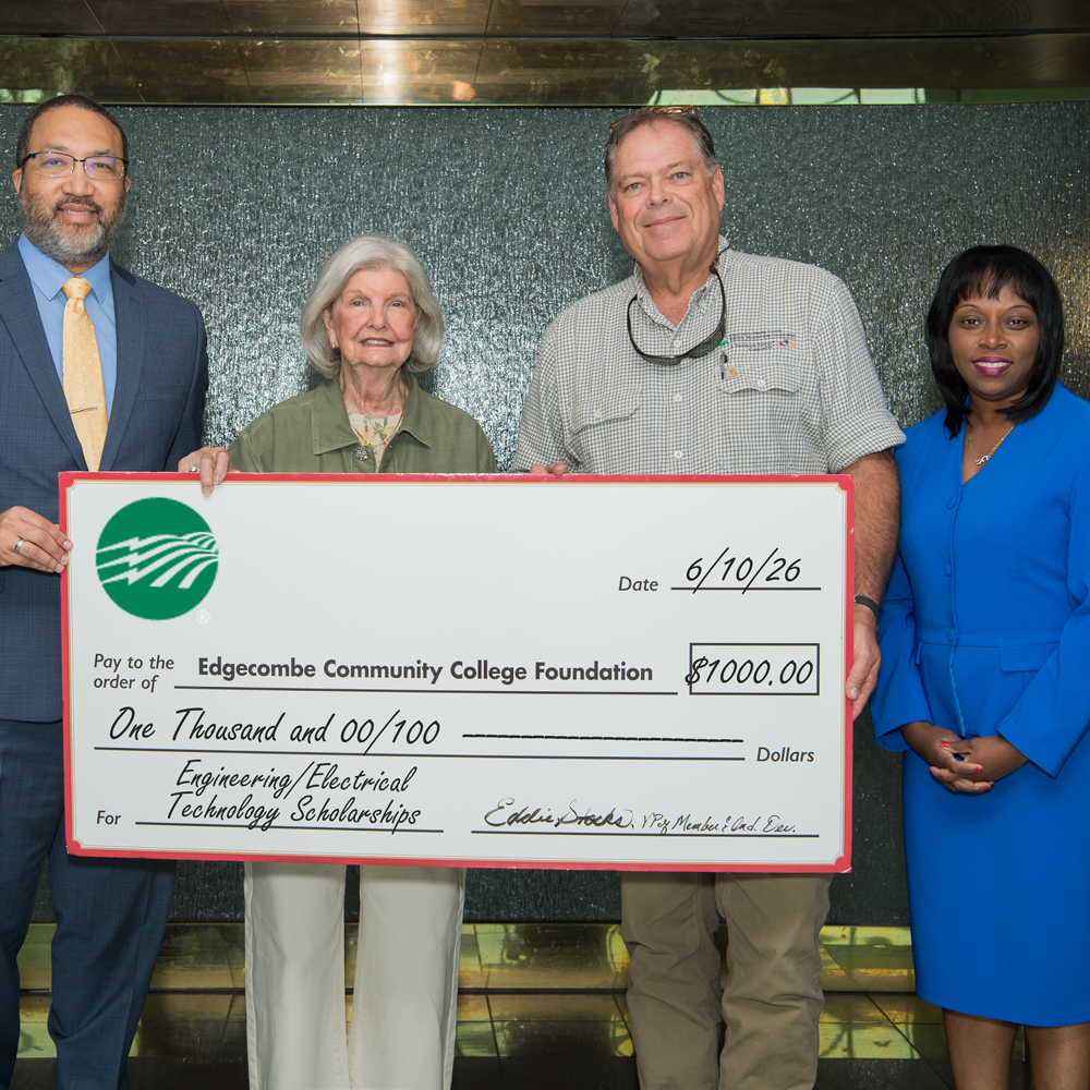Two males and two females holding a large check
