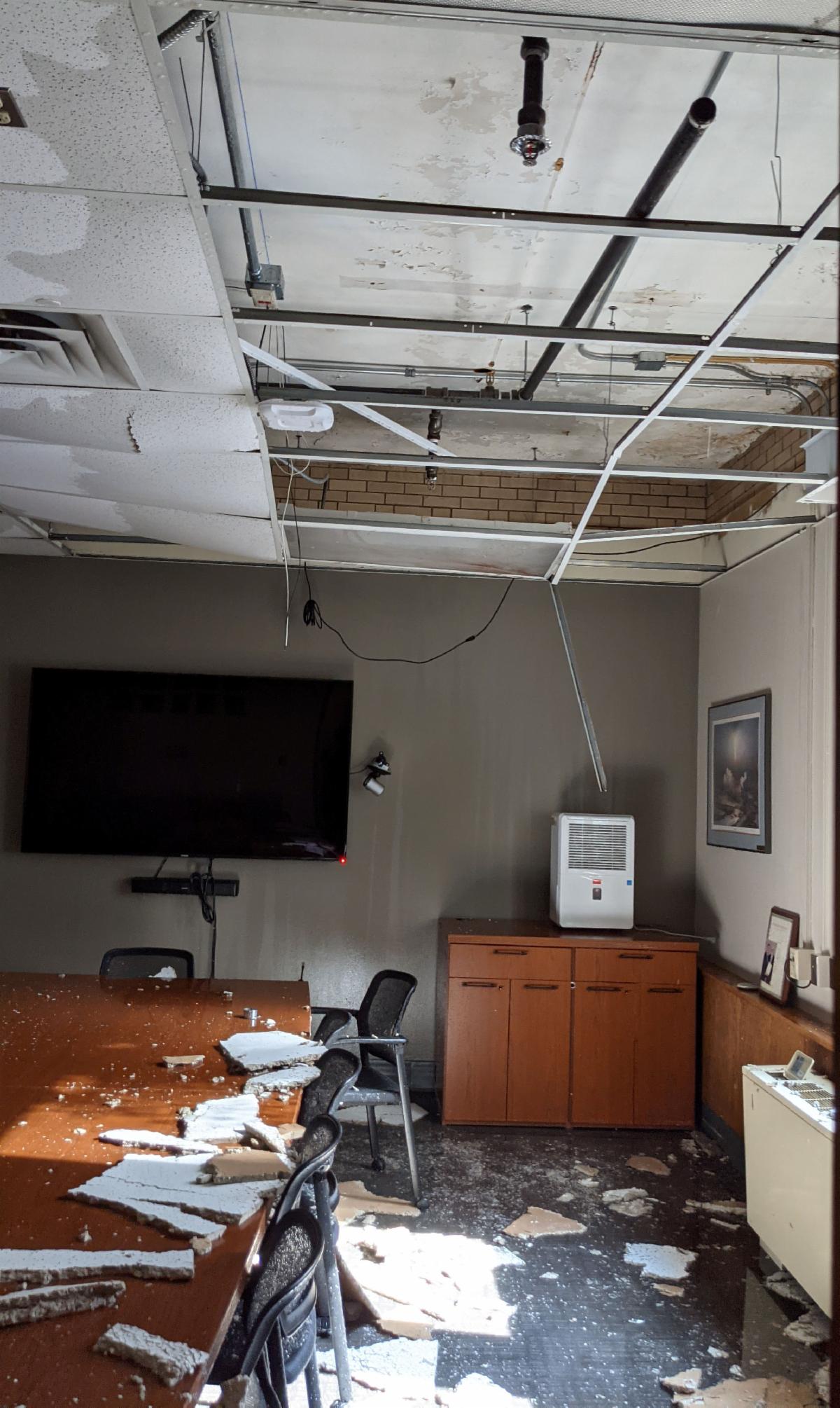 Image of conference room with major water damage, with collapsed ceiling tiles.
