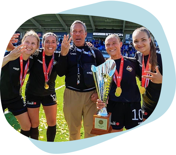 Man smiles and stands between four soccer players