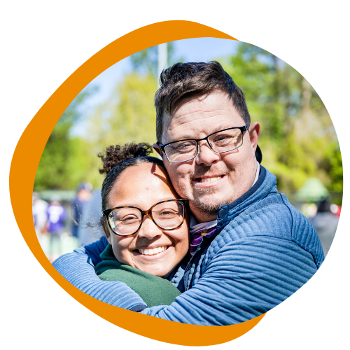 A man with down syndrome hugs a young woman. 