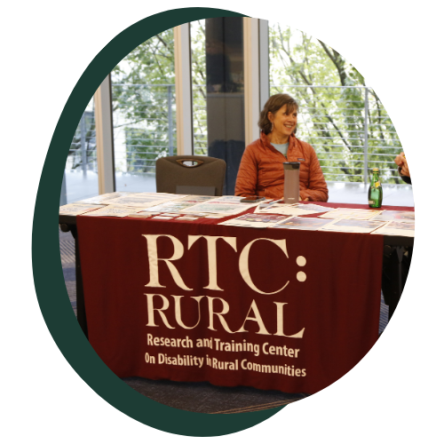 Catherine Ipsen sits at a table titled RTCRural at the 2025 APRIL conference. 