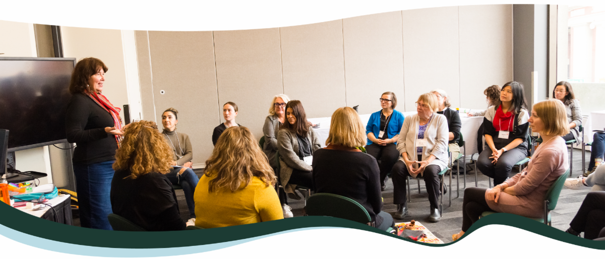 A group of people in a meeting listening to a woman speak. 