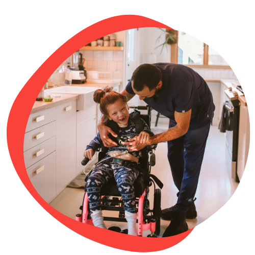 A father helps his daughter in her wheelchair. She is smiling and giggling.