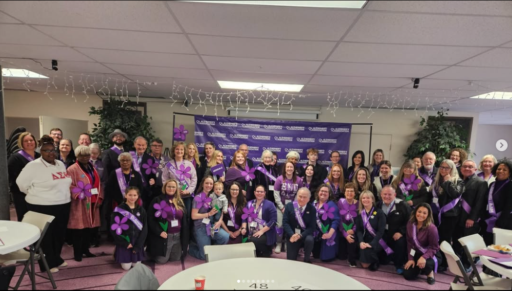 A large group of people in purple shirts posing for a photo