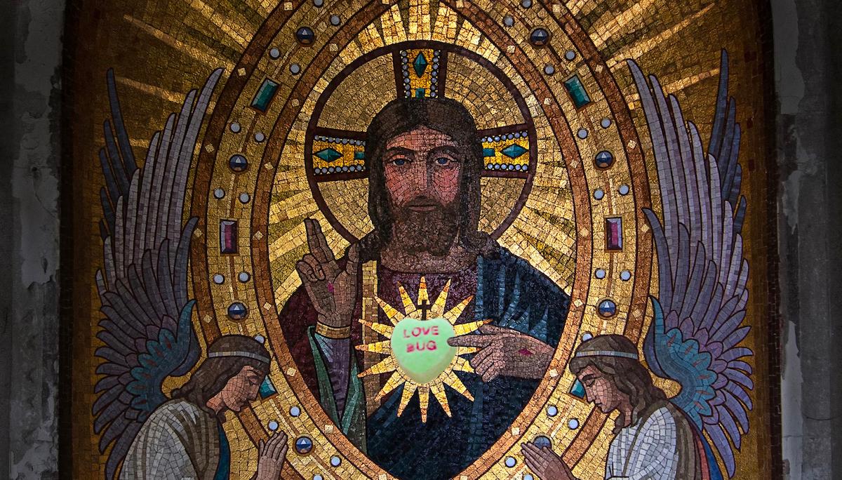 Medieval picture of grim looking sacred heart Jesus with a candy heart that says love bug superimposed over the sacred heart on his chest