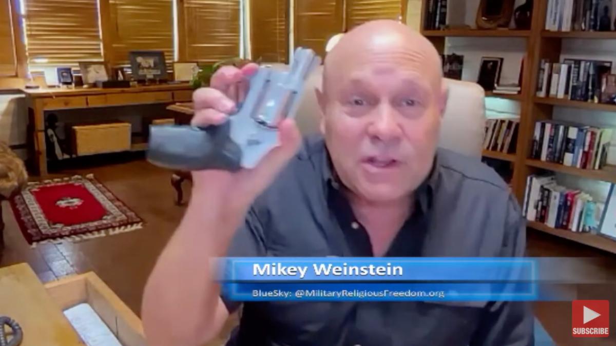 Mikey Weinstein holding up gun he took from his desk drawer