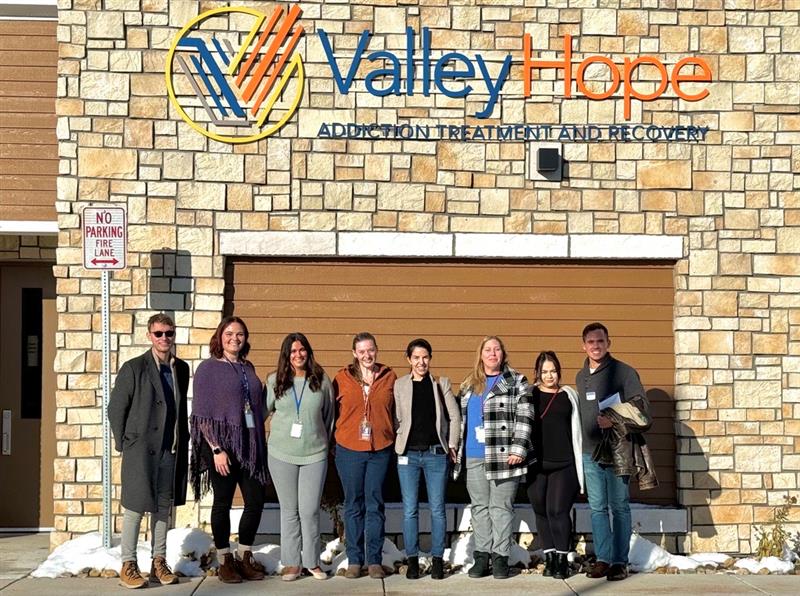 A group of 8 individuals stand in front of Valley Hope Addiction Treatment and Recovery Center