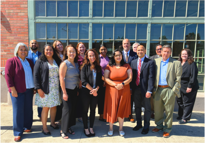 15 people posing for a photo outside a building.