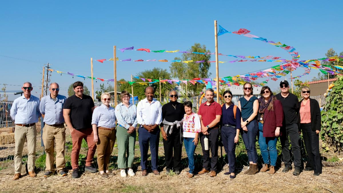 Multiple people posing for photo in field.
