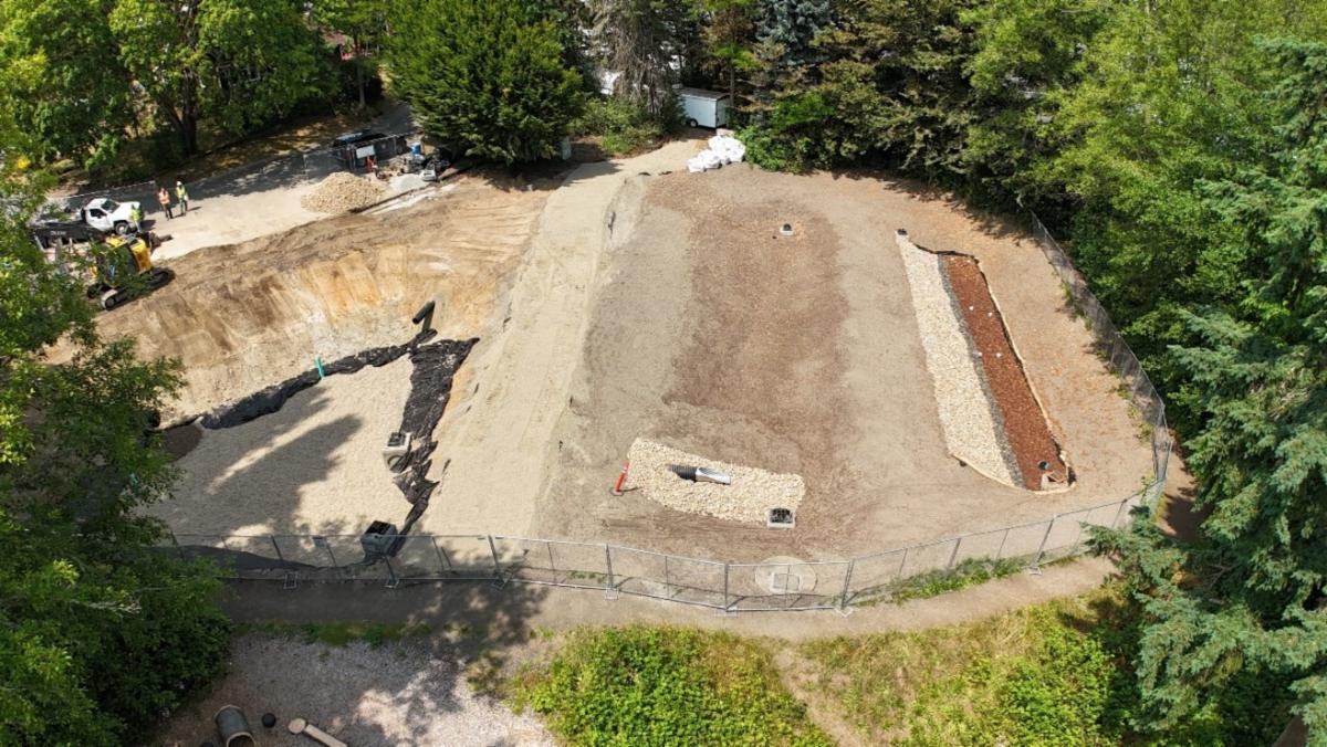 An aerial view of the stormwater retrofit project in Nelson Park. This is a dirt space with two levels that have been excavated. 