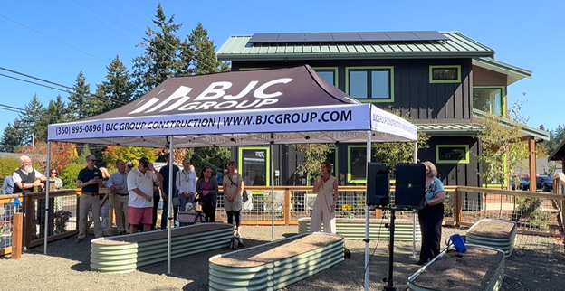 People standing outside listening to the speaker in front of the Nordic Cottages.