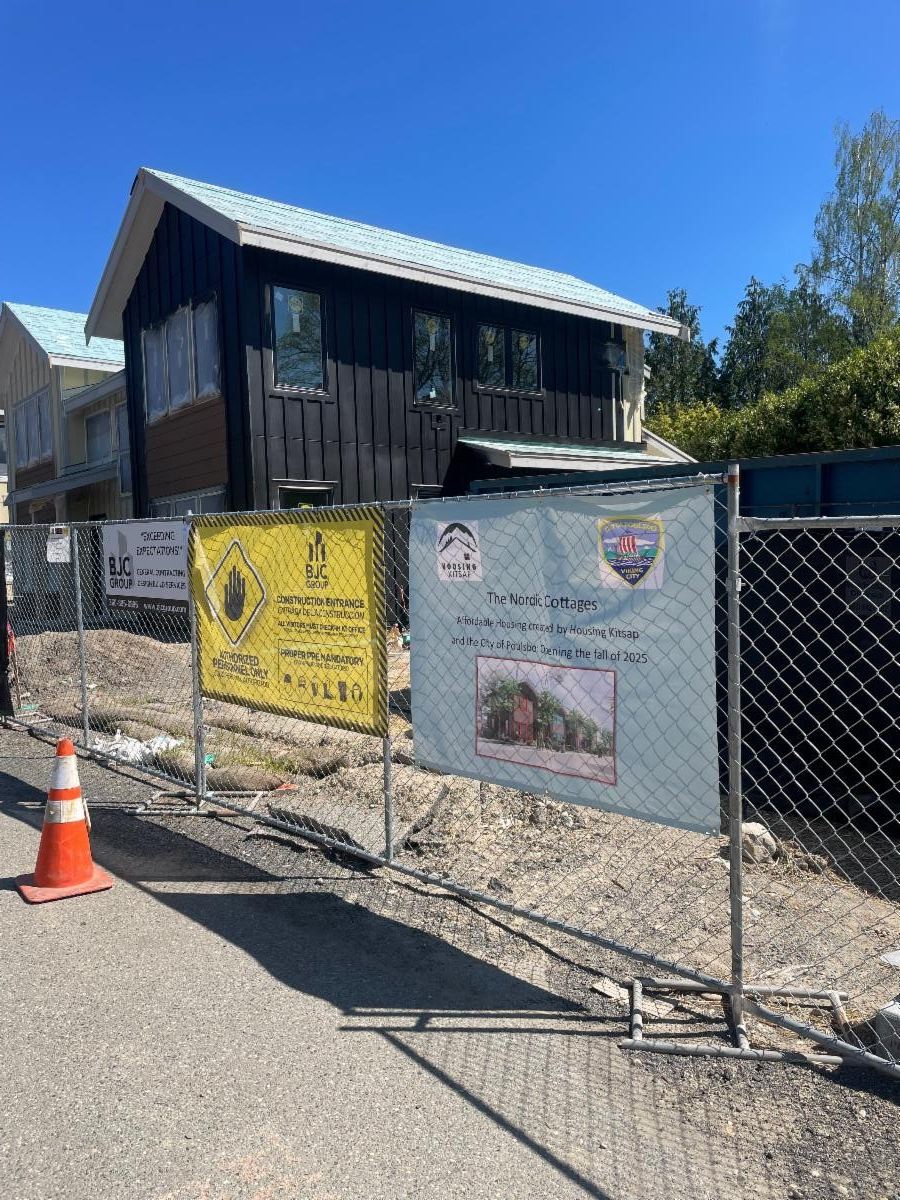 A view from the street of the exterior of Nordic Cottages in the process of being built. A chain link fence is between the street and the project.