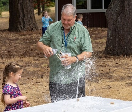 Little girl and father playing with a water station in a park.