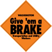 A gold "Give 'em a Brake" sign reminding drivers to use caution when transportation and utility worker road crews are in work zones on the roads.