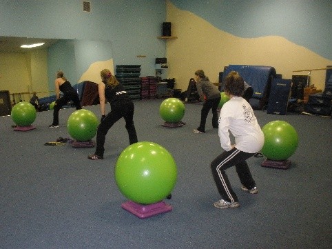 people stretching in an exercise class with big green exercise balls.