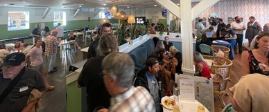 A group of people talking with each other with food and drinks.