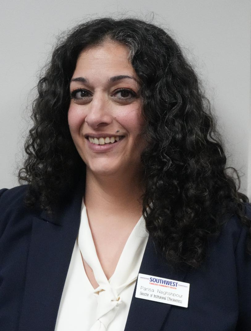 Woman smiling wearing black jacket, white shirt and a name tag