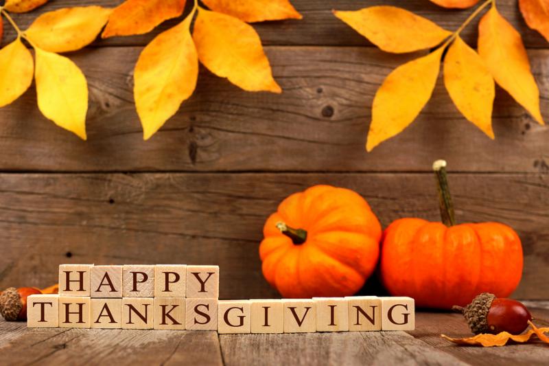 Happy Thanksgiving wooden blocks against a rustic wood background with autumn leaves and pumpkins