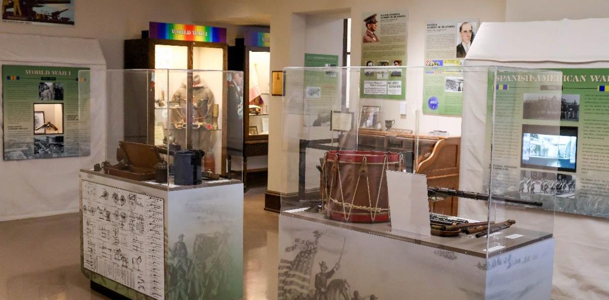 Exhibit area featuring a Seminole Wars informational panel with images and text, next to a digital display showing two service members saluting in front of an American flag with the title Polk County Land of Heroes.