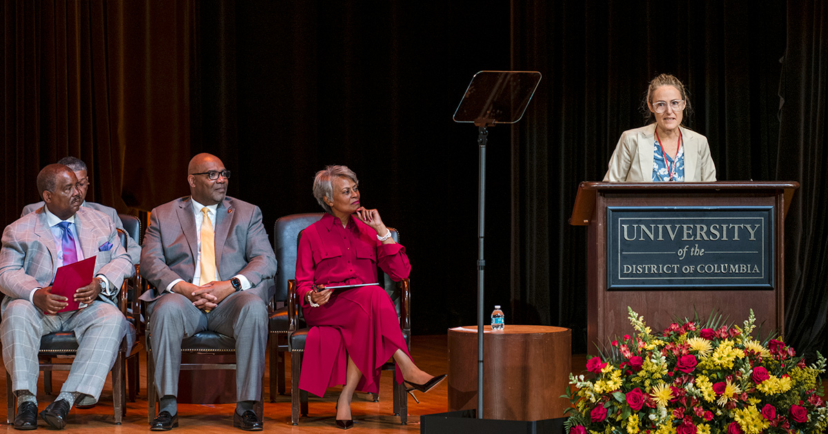 Professor Amanda Huron presents a Convocation lecture as UDC Board Chair Warner H Session Chief Academic Officer April Massey and President Maurice D Edington look on