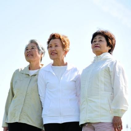 Trio of senior Asian women standing together in front of a blue sky