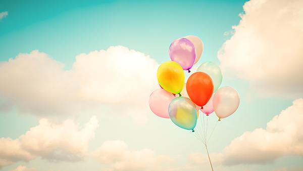 Colorful balloons in a blue sky with fluffy white clouds