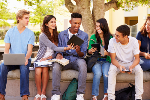 Group of adolescents sitting in front of a tree