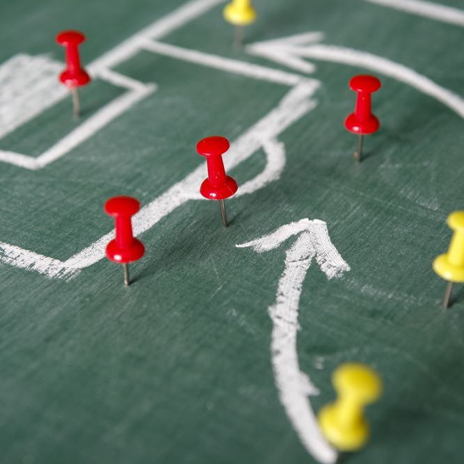 Drawing and push pins on a chalk board representing a play in soccer