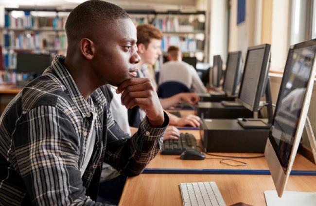 Young Black male presenting person working on a computer