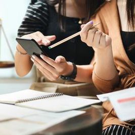 Close-up, two female lawyers sitting in an office looking at a cell phone