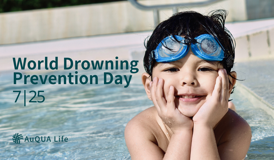 A child with blue swim goggles rests at the edge of a pool, smiling. Text reads, "World Drowning Prevention Day 7/25." AuQUA Life logo is visible.