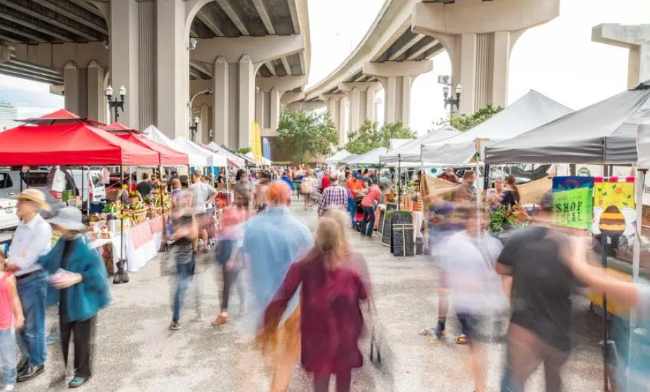 Shoppers browsing tents at the Riverside Arts Market under the bridge