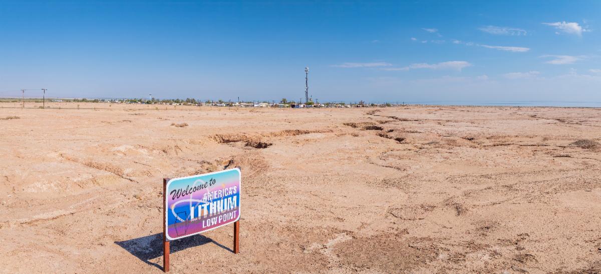 Dry valley with blue sky in background. Sign that reads Welcome to Americas Lithium Low Point in ground.