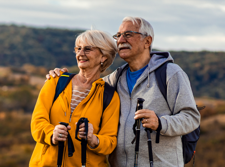 Two older adults happily hiking 