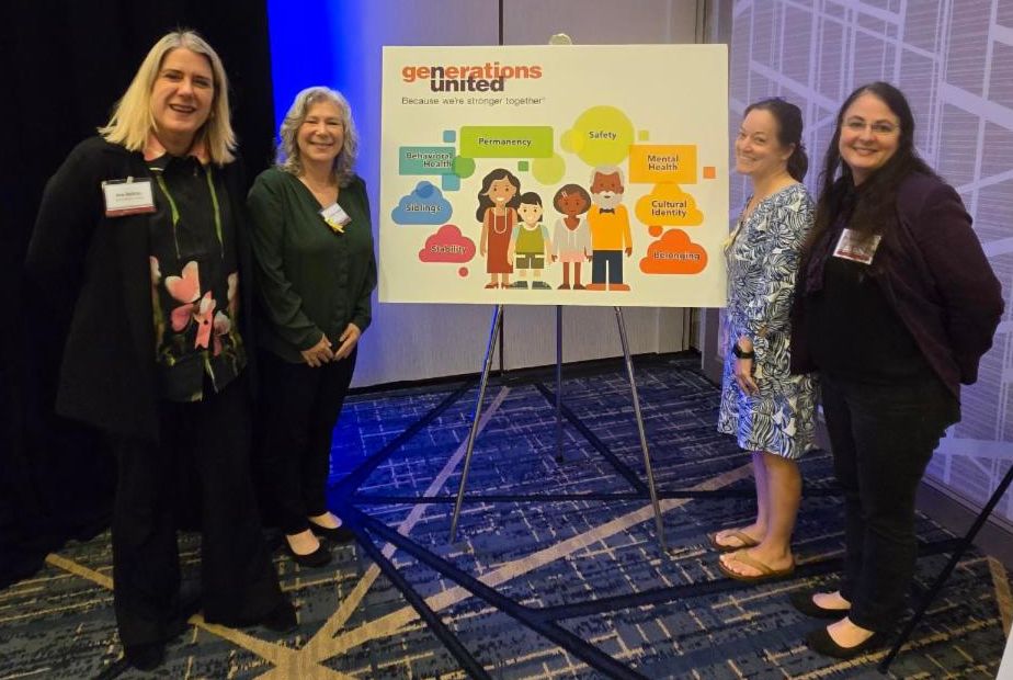 Four women pose with a poster