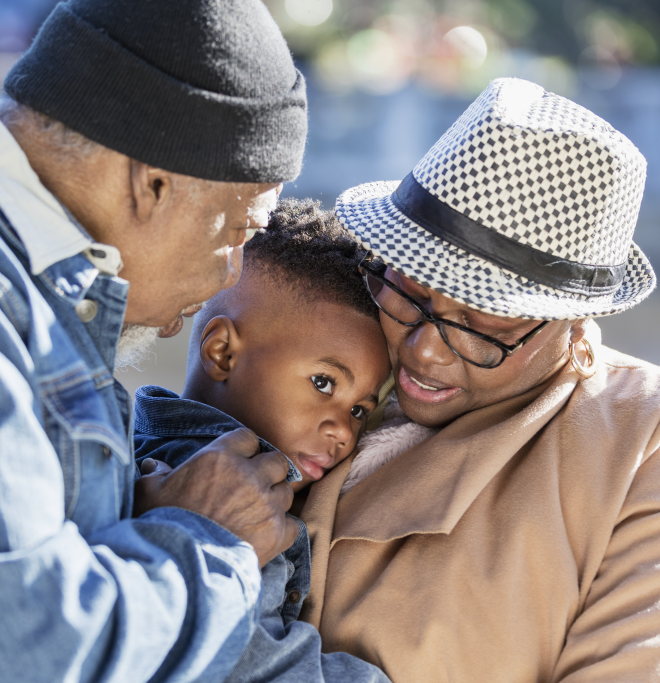 A Black grandmother and grandfather hold and comfort their grandchild